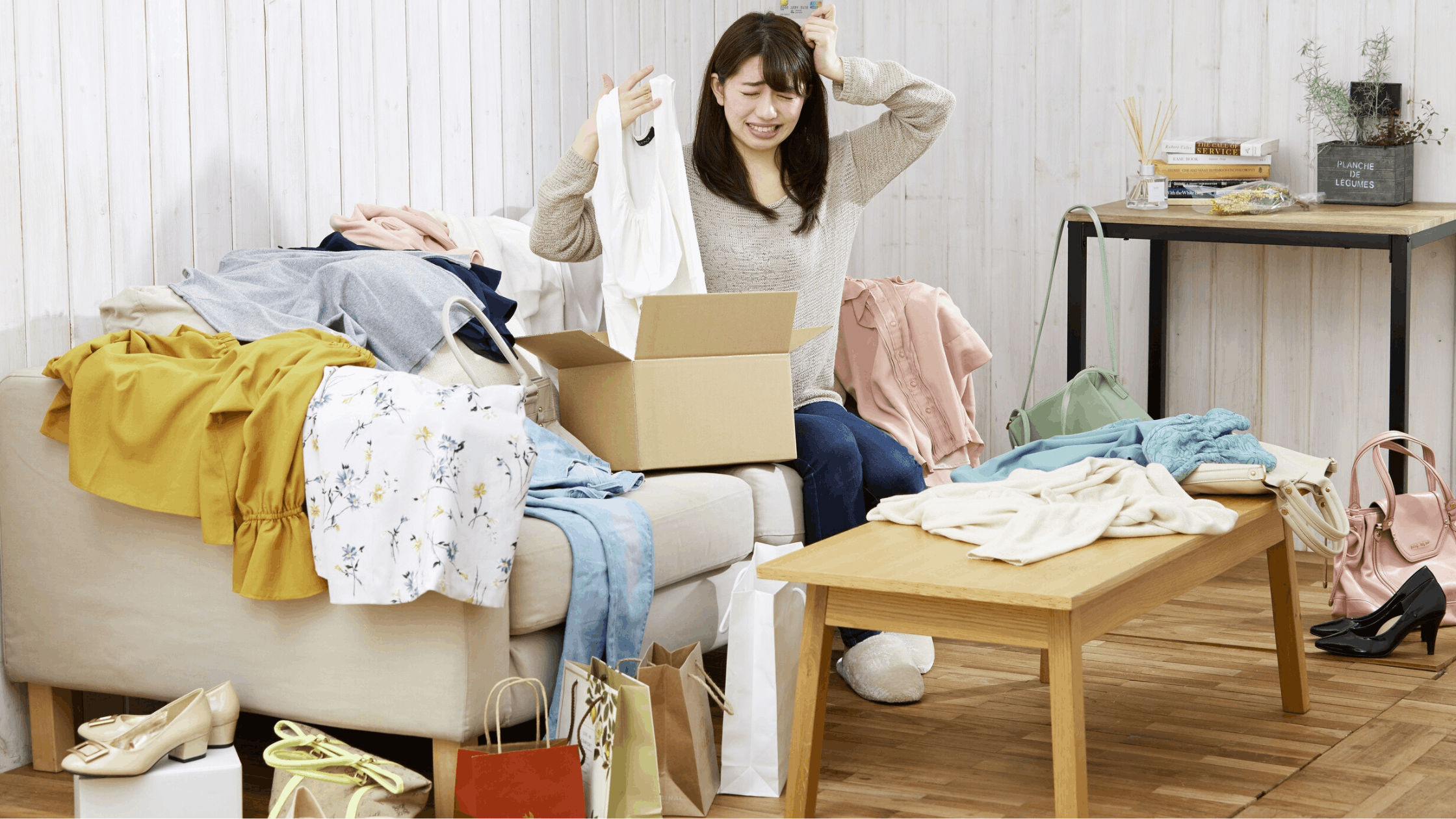 Dark haired woman surrounded by shopping bags and a clothes donation box wondering why am I broke with a good job.